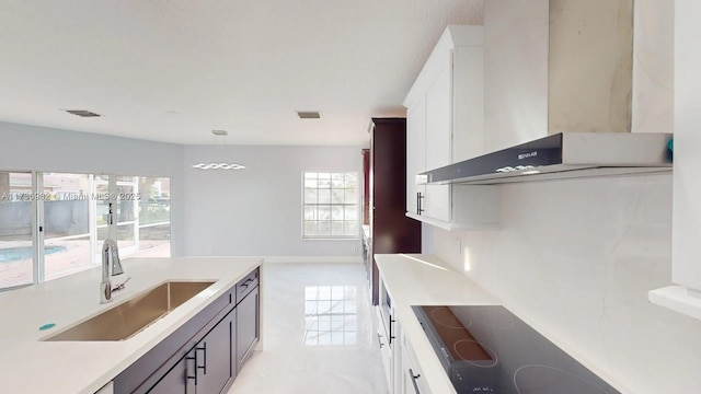 kitchen with white cabinetry, sink, black electric cooktop, and wall chimney exhaust hood