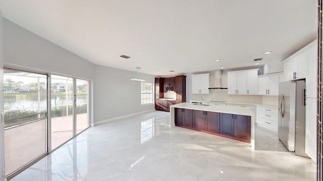 kitchen with white cabinets, sink, stainless steel refrigerator, and wall chimney exhaust hood