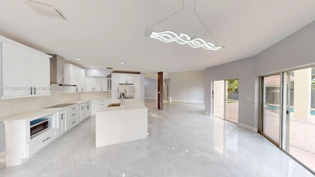 kitchen featuring a center island, appliances with stainless steel finishes, pendant lighting, wall chimney range hood, and white cabinets