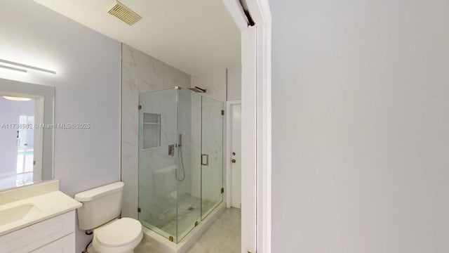 bathroom featuring vanity, an enclosed shower, and toilet