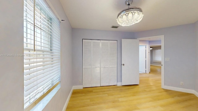 unfurnished bedroom featuring multiple windows, a closet, and light hardwood / wood-style flooring