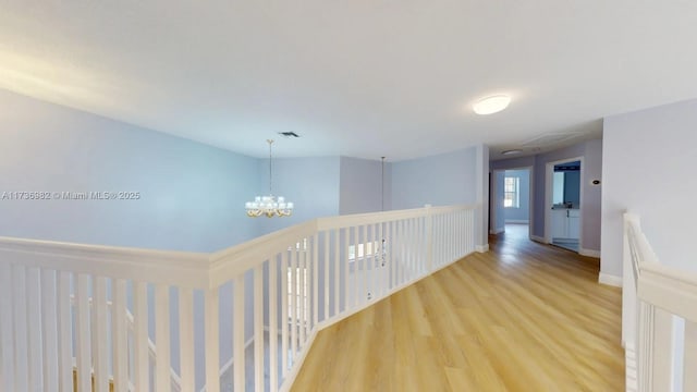 corridor with hardwood / wood-style flooring and a chandelier