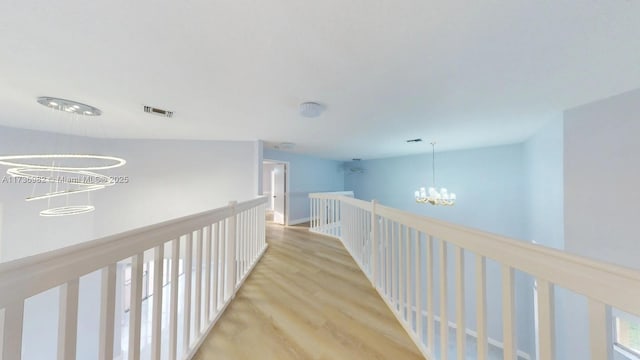 hallway with an inviting chandelier and light hardwood / wood-style floors