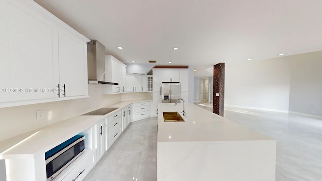 kitchen with white cabinetry, sink, stainless steel appliances, a center island with sink, and wall chimney exhaust hood