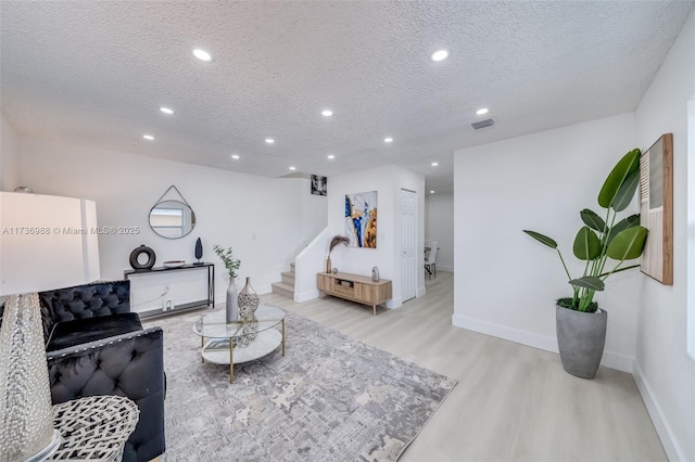 living room with a textured ceiling and light hardwood / wood-style floors