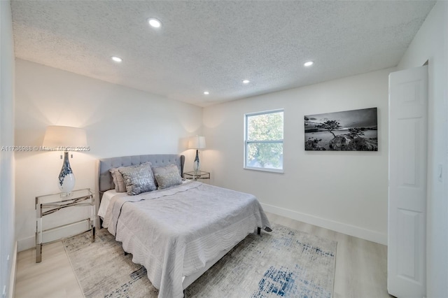 bedroom with light hardwood / wood-style floors and a textured ceiling