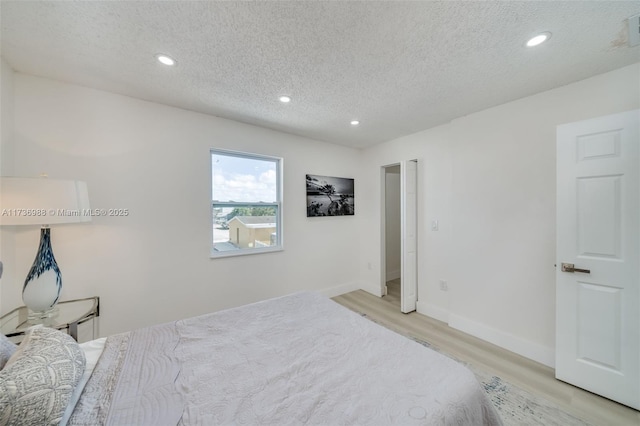 bedroom featuring a textured ceiling and light hardwood / wood-style flooring