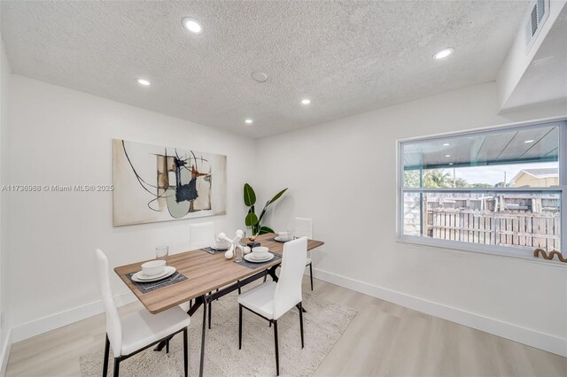 dining space featuring a textured ceiling and light hardwood / wood-style floors