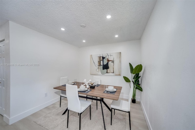 dining space with a textured ceiling and light hardwood / wood-style floors