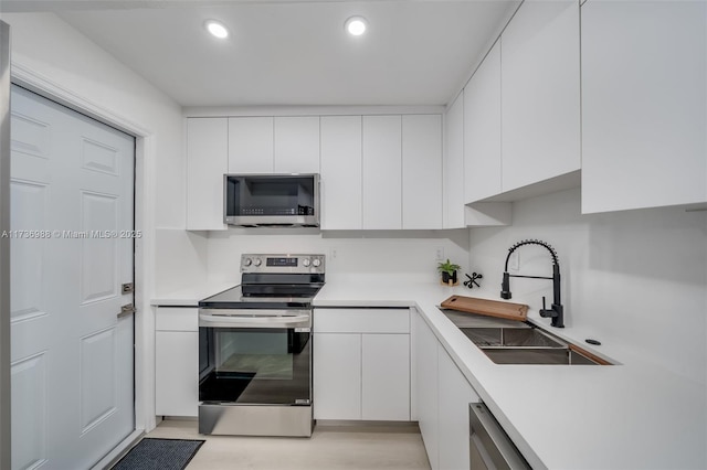 kitchen with stainless steel appliances, sink, and white cabinets