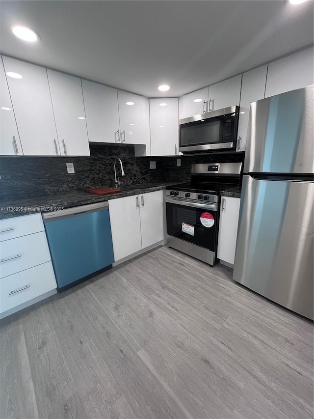 kitchen featuring sink, white cabinetry, backsplash, stainless steel appliances, and light hardwood / wood-style floors