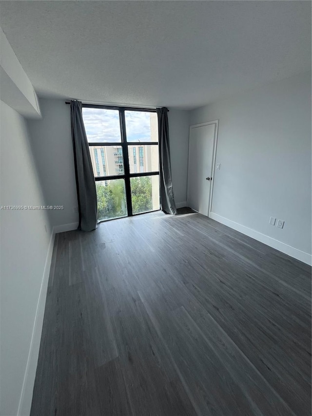 spare room with dark wood-type flooring, floor to ceiling windows, and a textured ceiling