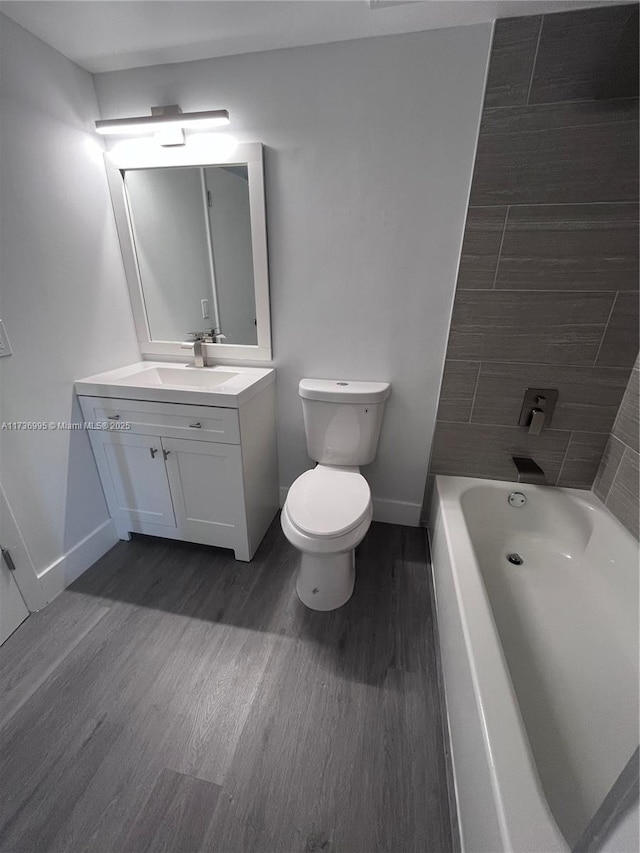 full bathroom with vanity, hardwood / wood-style floors, tiled shower / bath combo, and toilet