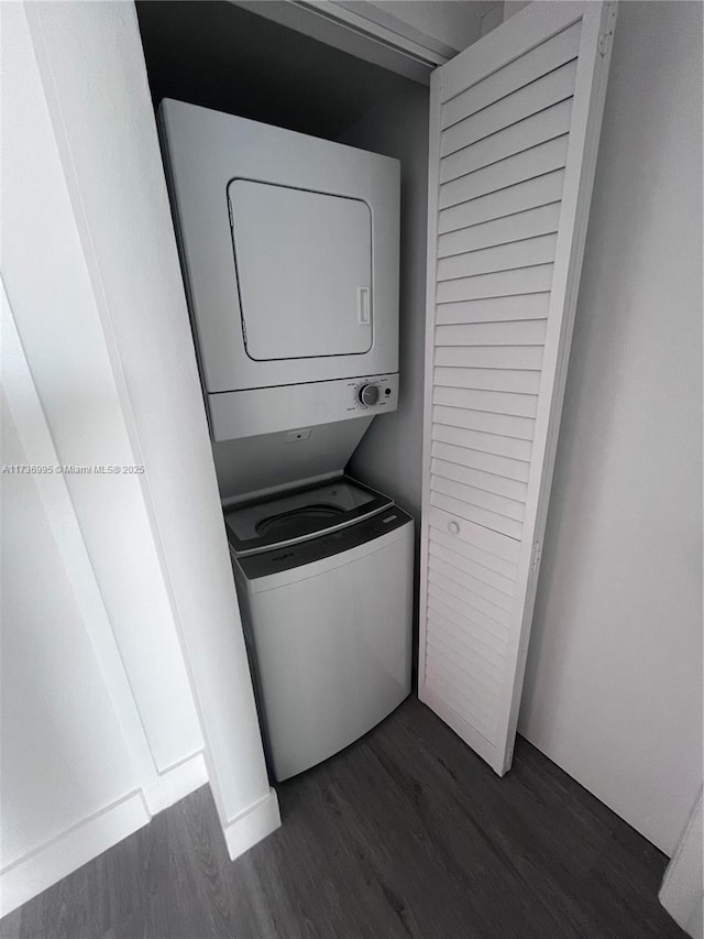 laundry room with dark wood-type flooring and stacked washer and clothes dryer