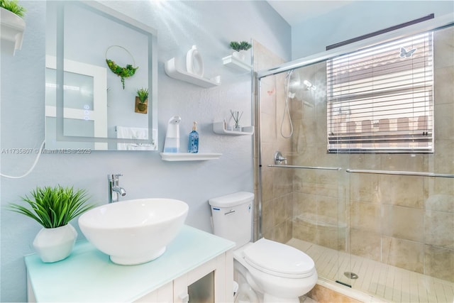 bathroom featuring vanity, a shower with shower door, and toilet