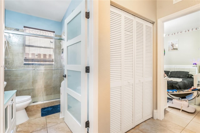 bathroom with tile patterned floors, toilet, a shower with shower door, and vanity