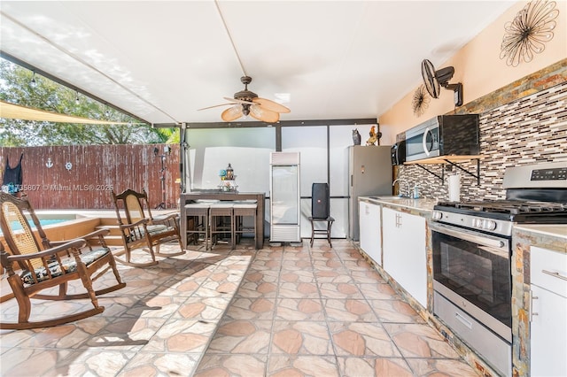 kitchen with sink, ceiling fan, appliances with stainless steel finishes, white cabinetry, and tasteful backsplash