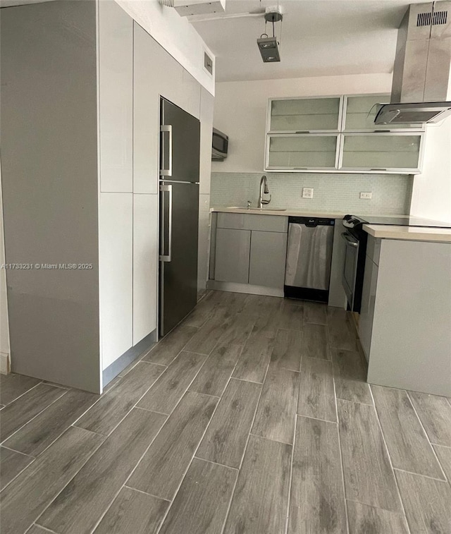 kitchen with sink, island range hood, backsplash, and appliances with stainless steel finishes