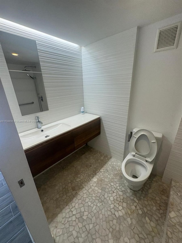 bathroom with vanity, a shower, and toilet