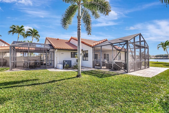 back of house featuring cooling unit, a yard, a water view, and glass enclosure