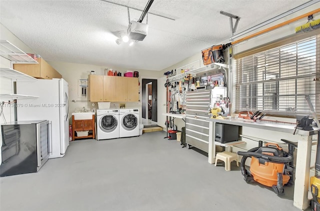 garage featuring sink, white fridge, washing machine and clothes dryer, a garage door opener, and a workshop area