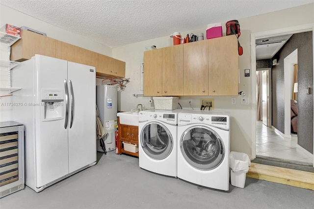 laundry room featuring washer and dryer, water heater, beverage cooler, cabinets, and a textured ceiling