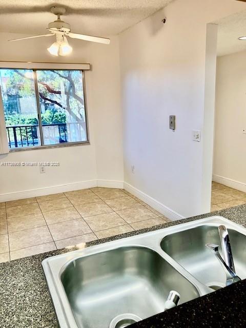 kitchen featuring light tile patterned flooring, ceiling fan, sink, and a textured ceiling