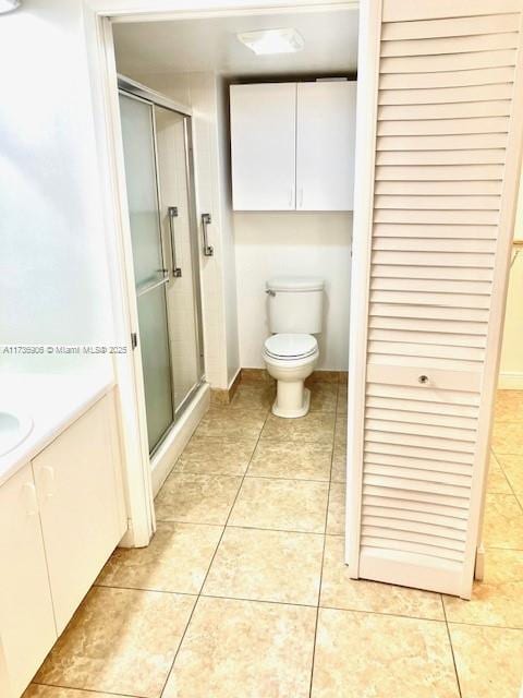 bathroom with an enclosed shower, vanity, tile patterned floors, and toilet