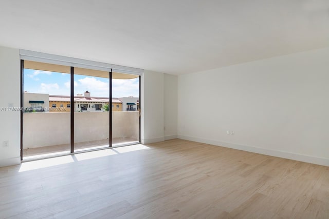 unfurnished room featuring a wall of windows and light hardwood / wood-style flooring