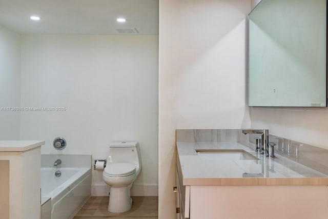 bathroom featuring sink, wood-type flooring, toilet, and a tub to relax in