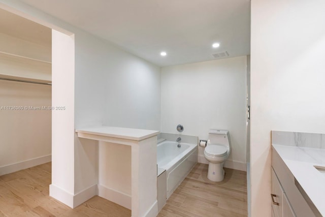 bathroom featuring a washtub, vanity, wood-type flooring, and toilet