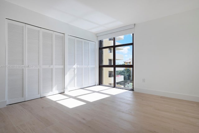 unfurnished bedroom with light hardwood / wood-style flooring and floor to ceiling windows