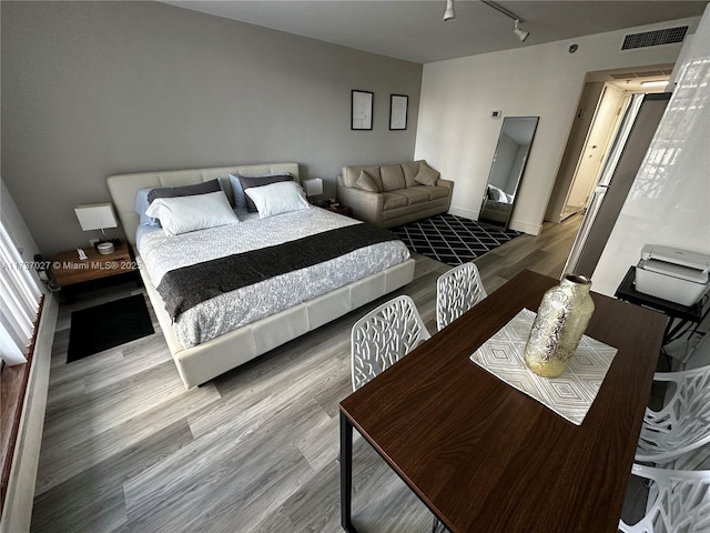 bedroom featuring hardwood / wood-style flooring and rail lighting