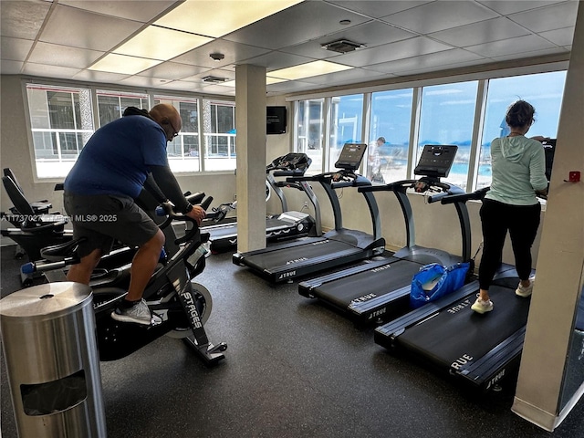 gym featuring a paneled ceiling and a wealth of natural light