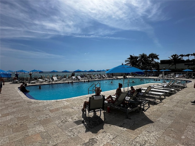 view of pool featuring a water view and a patio