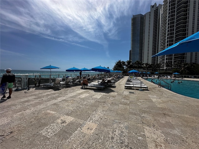 view of swimming pool featuring a patio and a water view