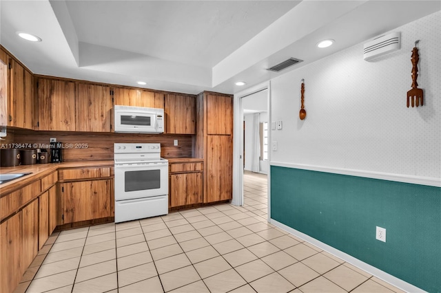 kitchen with white appliances, a raised ceiling, and light tile patterned flooring