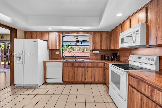 kitchen with sink, white appliances, a wealth of natural light, and light tile patterned flooring