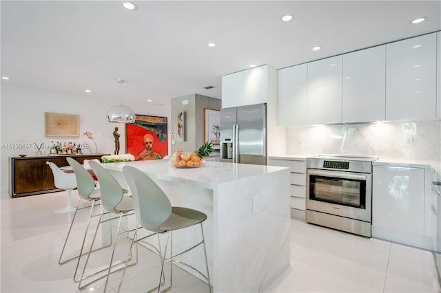 kitchen featuring white cabinetry, appliances with stainless steel finishes, a kitchen island, and pendant lighting