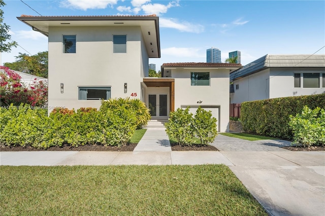 view of front of property featuring a garage, a front lawn, and french doors