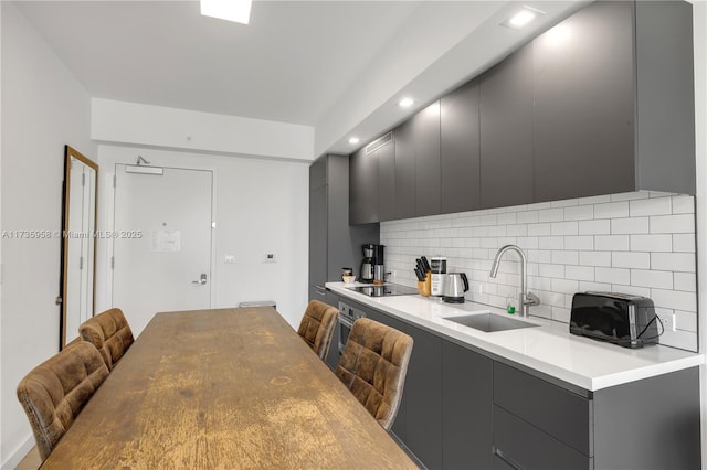 kitchen with sink, gray cabinetry, backsplash, black electric stovetop, and oven