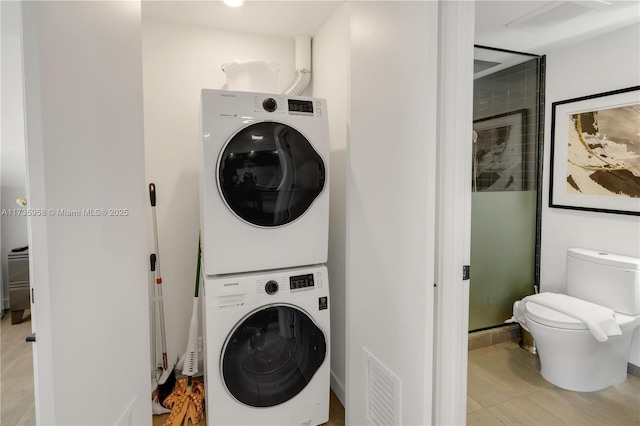 laundry area with stacked washer and dryer and light tile patterned floors