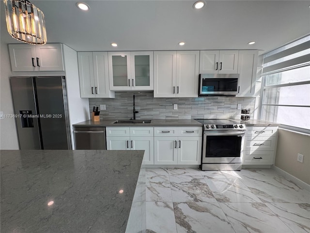 kitchen with decorative light fixtures, sink, white cabinets, backsplash, and stainless steel appliances