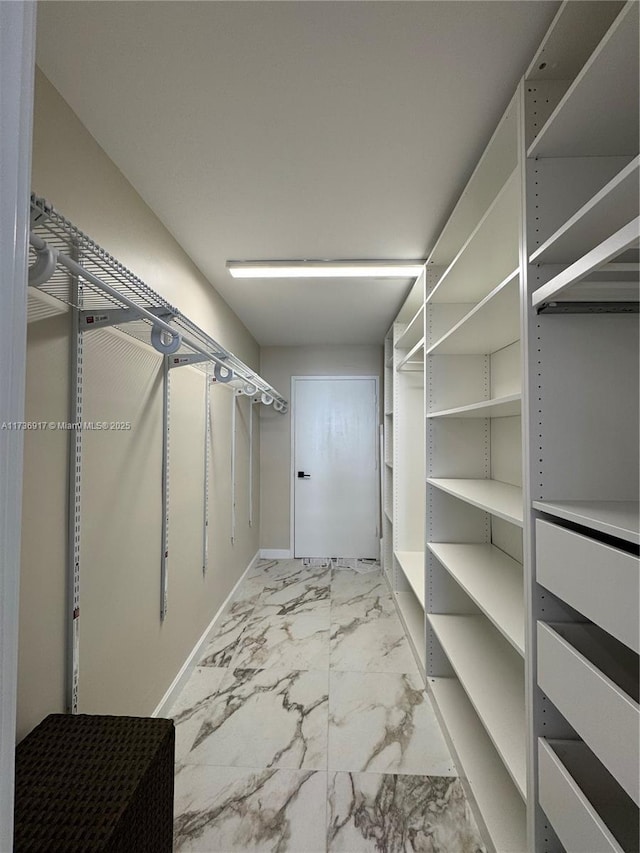 walk in closet featuring marble finish floor