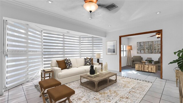 living room with light tile patterned flooring, ornamental molding, a textured ceiling, and ceiling fan