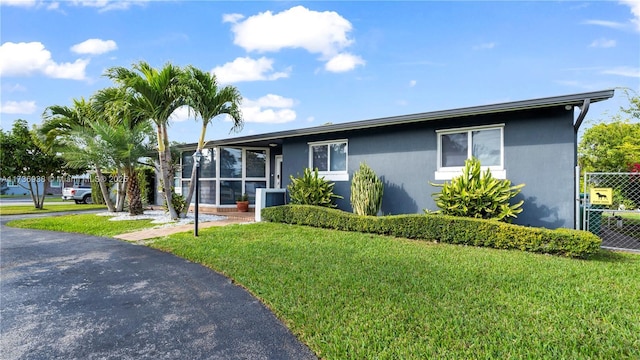 ranch-style home with a front lawn and fence