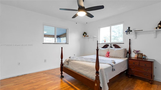 bedroom featuring multiple windows, ceiling fan, baseboards, and wood finished floors