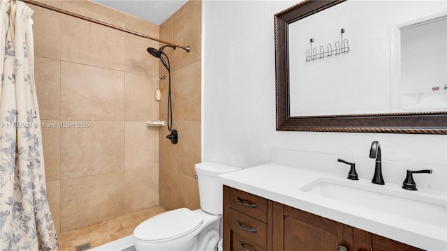 bathroom featuring toilet, vanity, and a tile shower