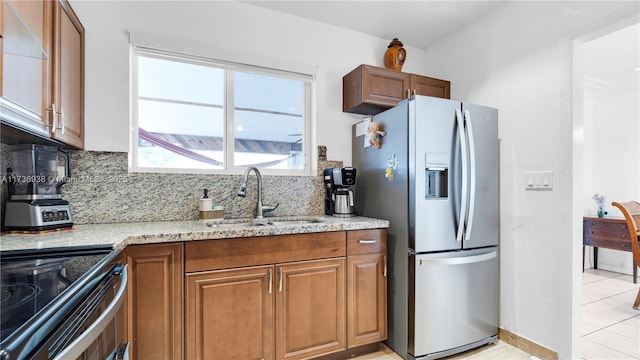 kitchen with a sink, brown cabinets, tasteful backsplash, and stainless steel fridge with ice dispenser