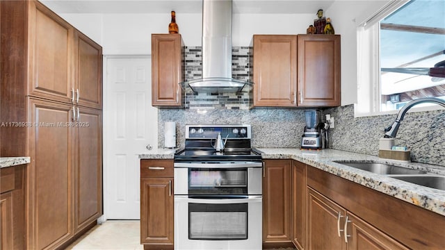 kitchen with light stone countertops, double oven range, decorative backsplash, exhaust hood, and a sink